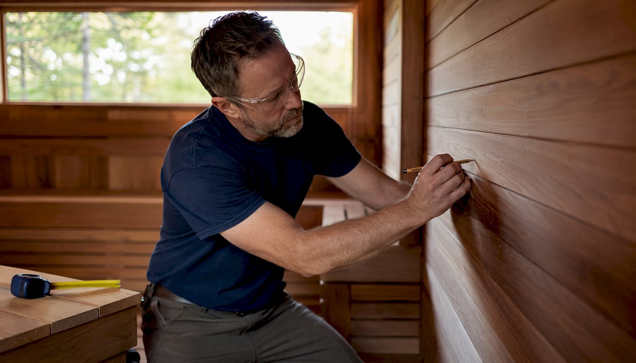 Homeowner marking wall for sauna heater installation