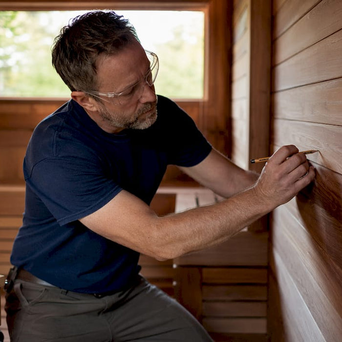 Homeowner marking wall for sauna heater installation