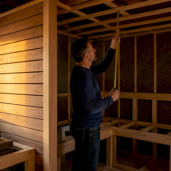 Sauna builder measuring ceiling height inside framed sauna