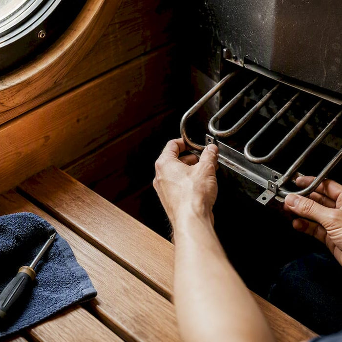 Hands removing sauna heating element in sauna