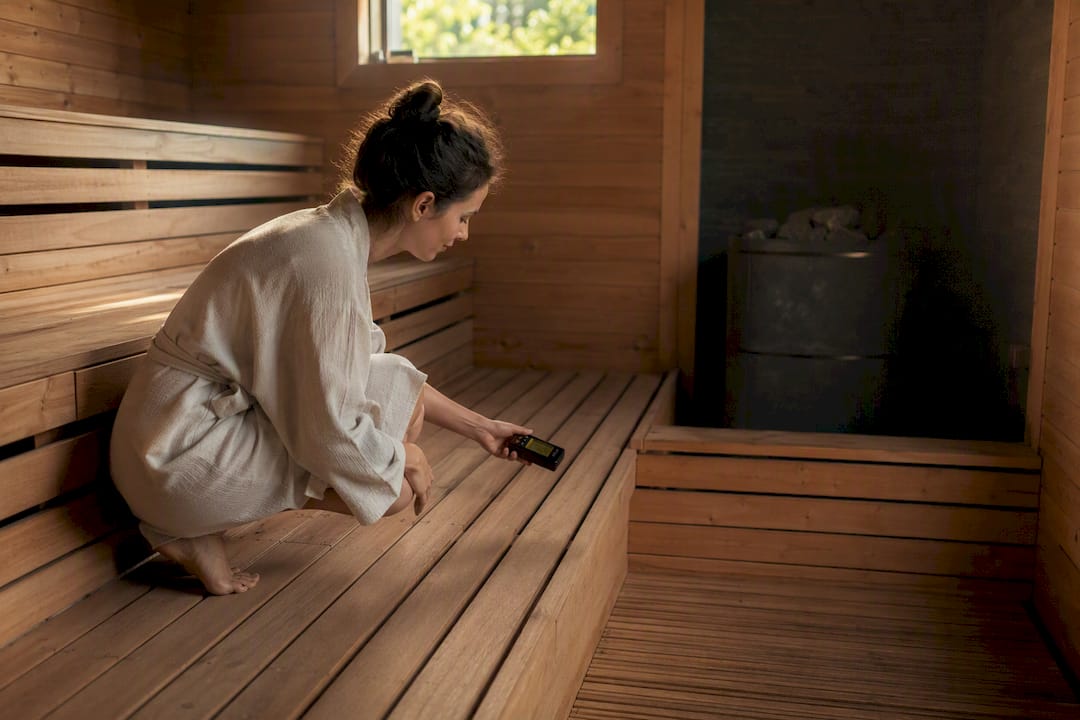 Hand measuring EMF inside sauna near wooden bench