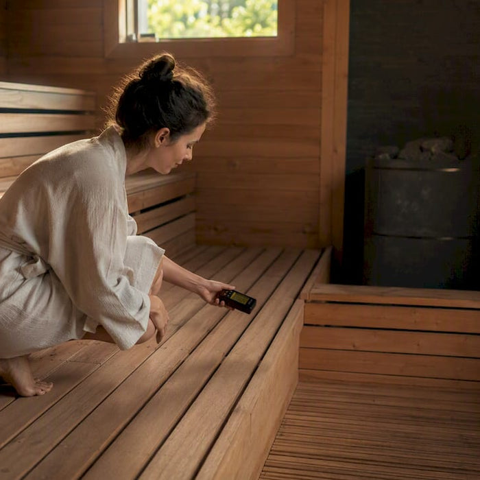 Hand measuring EMF inside sauna near wooden bench