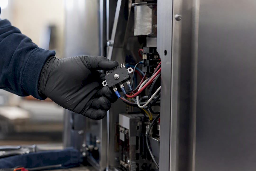 Technician holding sauna heater high limit switch