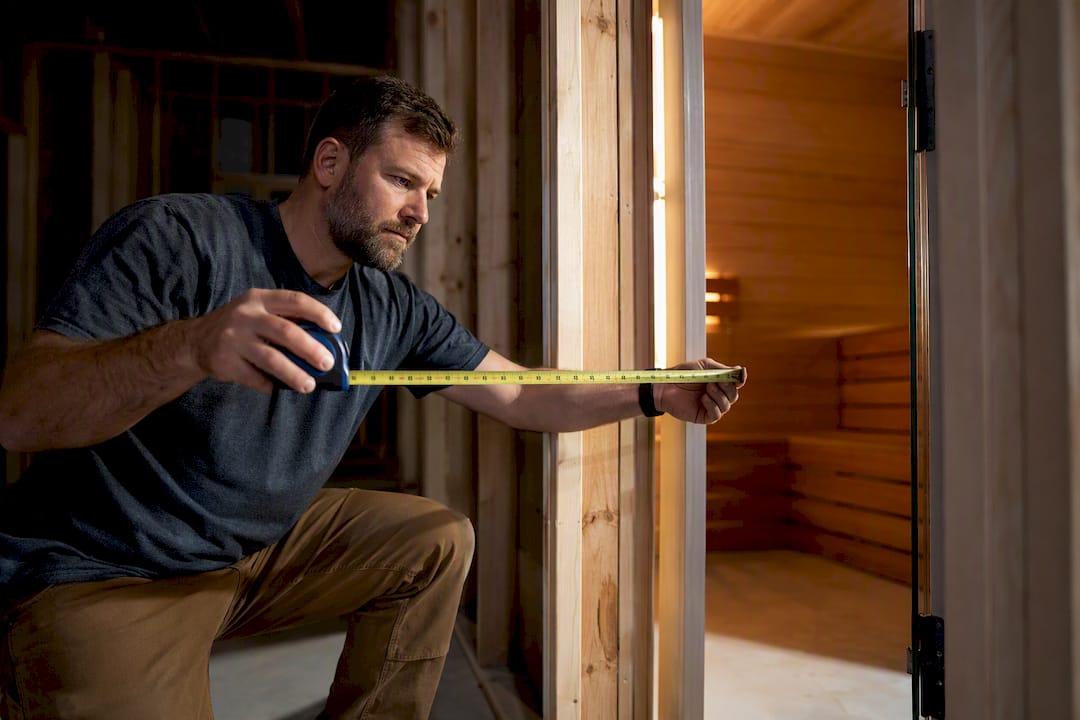 Builder measuring a sauna door rough opening