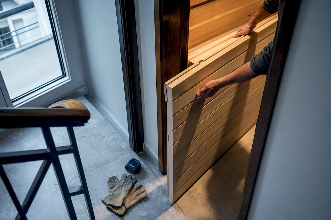 Flat-packed sauna panels entering narrow doorway