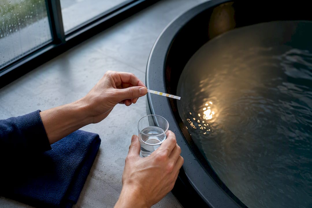Hands testing cold plunge water