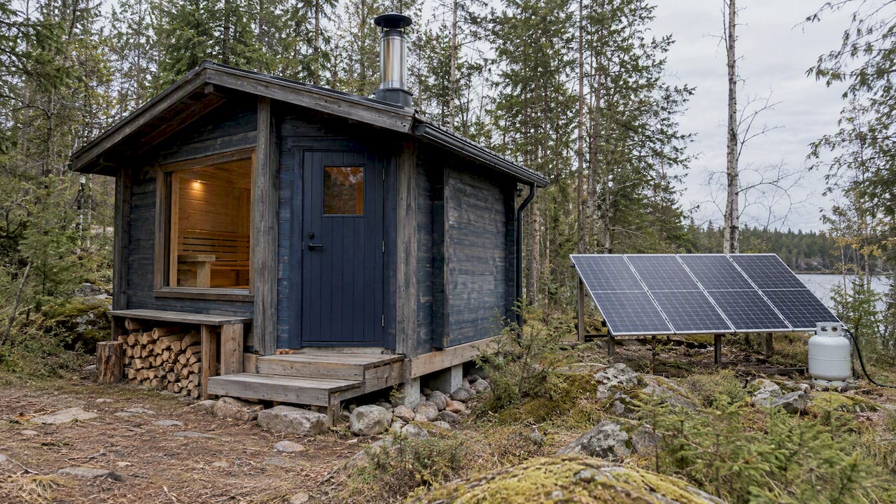 Off-grid sauna with chimney, solar panels, and propane