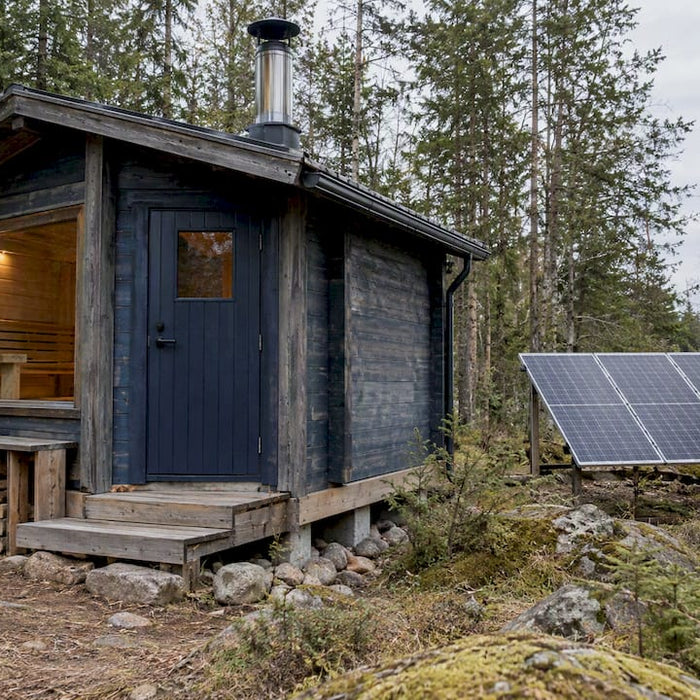 Off-grid sauna with chimney, solar panels, and propane